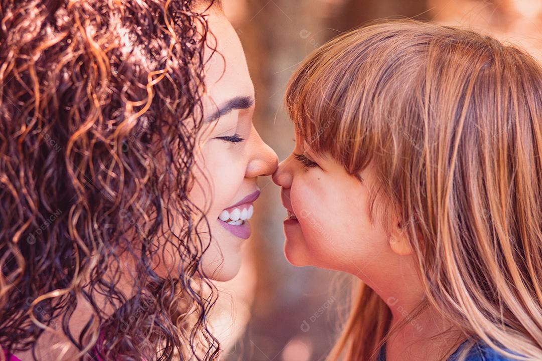 mãe e filha dando beijo de esquimó. Dia das Mães. Mãe afro e filha branca