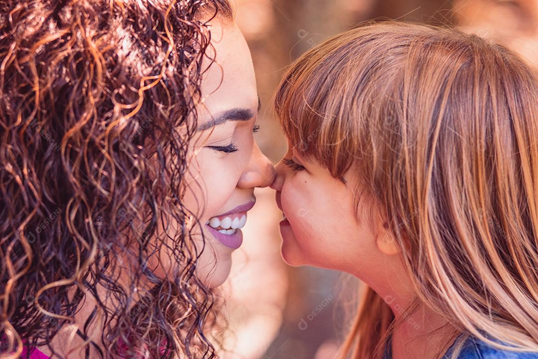 mãe e filha dando beijo de esquimó. Dia das Mães. Mãe afro e filha branca