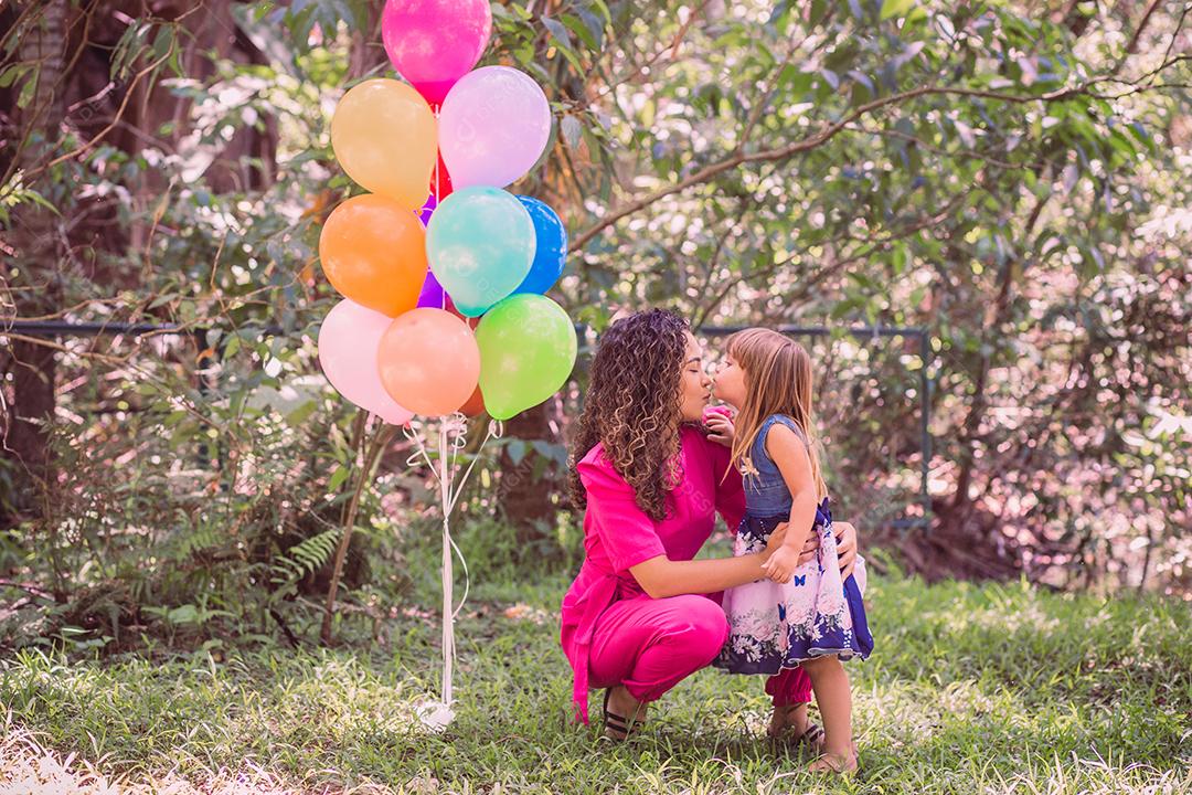 feliz mãe e filha no parque com balões.