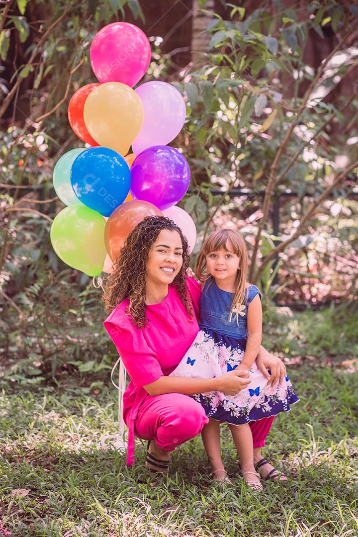 feliz mãe e filha no parque com balões.