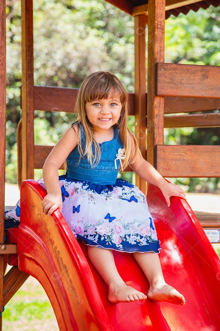 linda menina caucasiana brincando no playground.