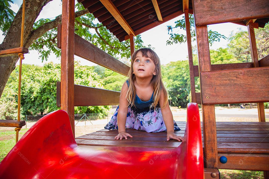 linda menina caucasiana brincando no playground.