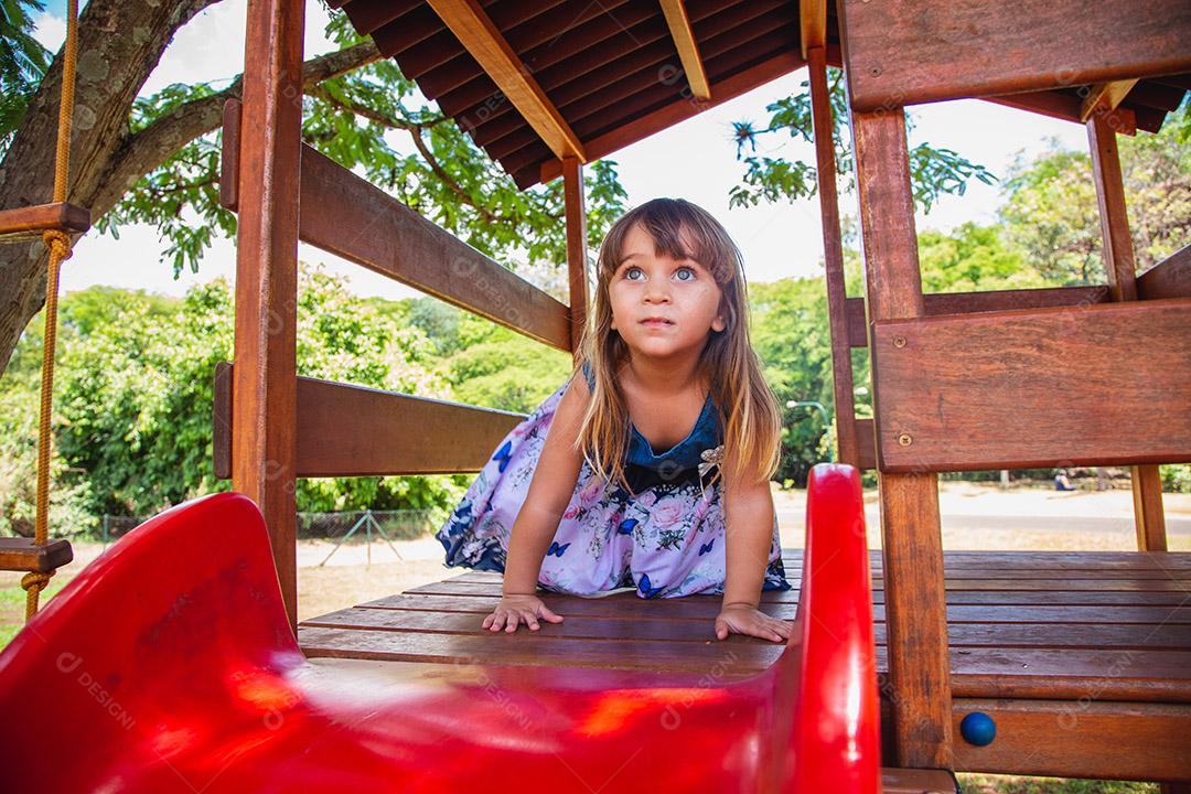 linda menina caucasiana brincando no playground.