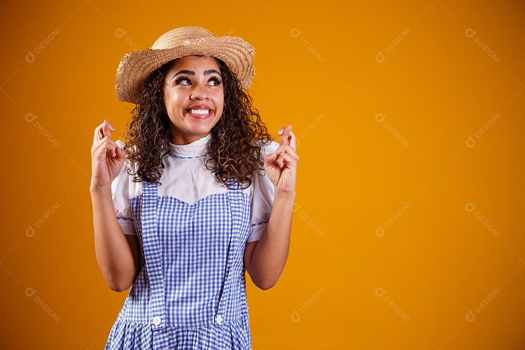 Mulher brasileira vestindo roupas típicas para a Festa Junina com dedos cruzados