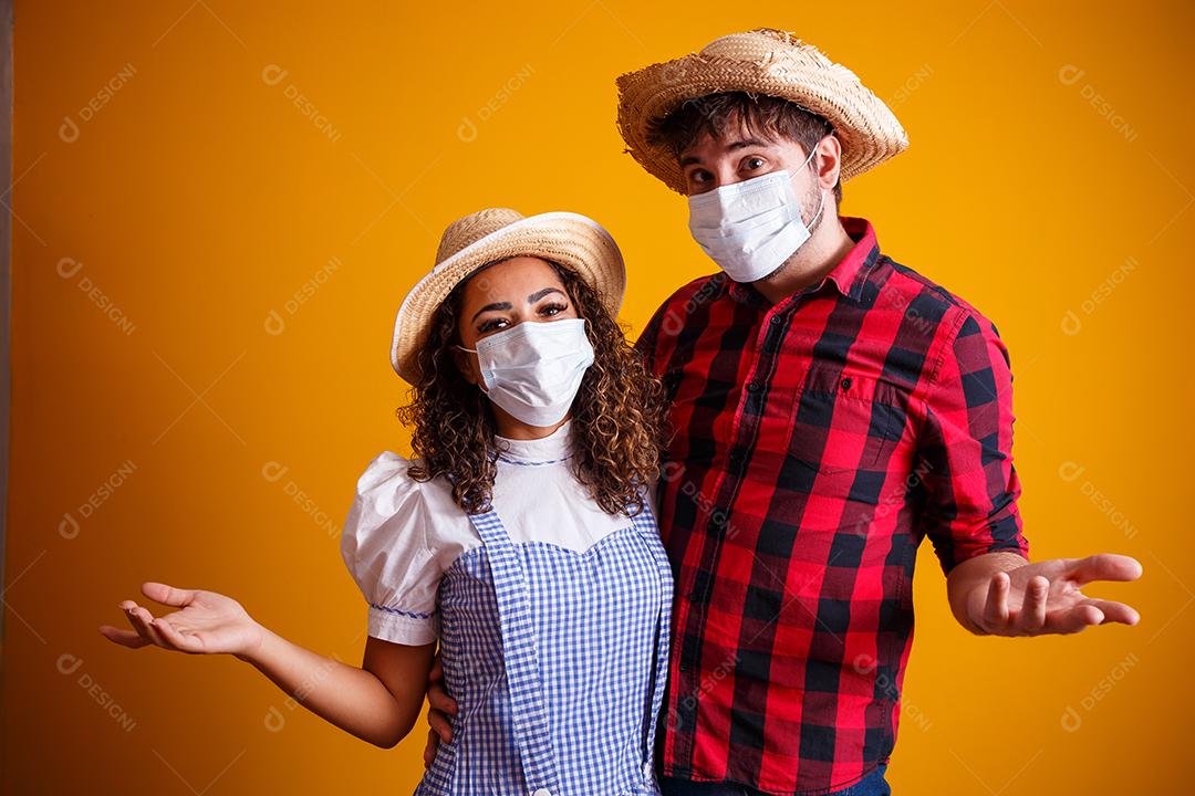 casal vestindo roupas típicas para a Festa Junina e máscara de proteção para prevenção do COVID-19.