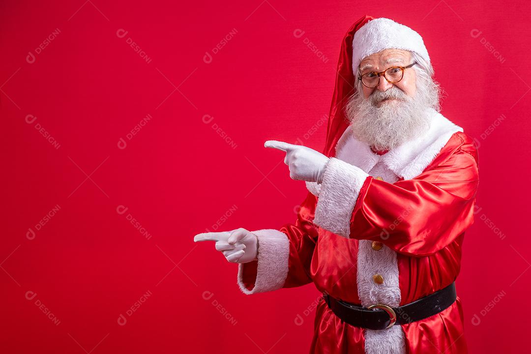 Engraçado feliz animado velho barbudo rosto de Papai Noel vestindo traje olhando para a câmera mostrando dedos apontando