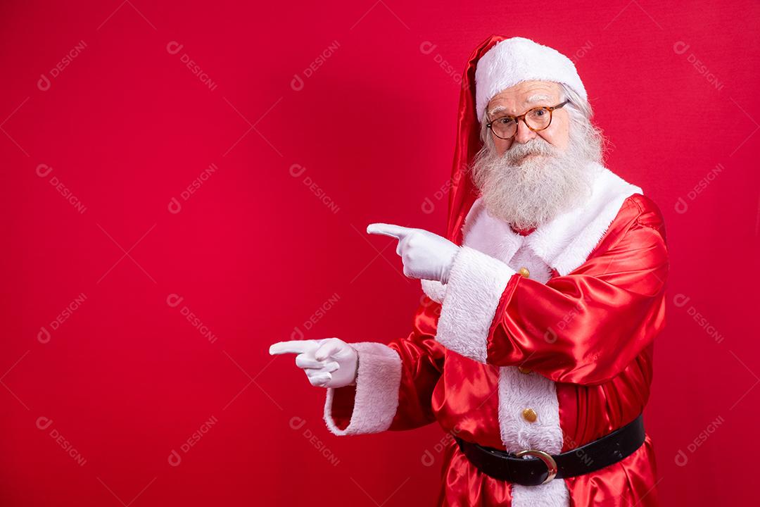 Engraçado feliz animado velho barbudo rosto de Papai Noel vestindo traje olhando para a câmera mostrando dedos apontando