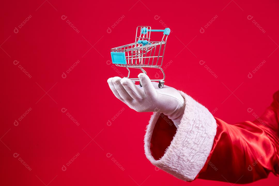 Papai Noel e o supermercado, ele está mostrando um mini carrinho. Natal e conceito de compras.