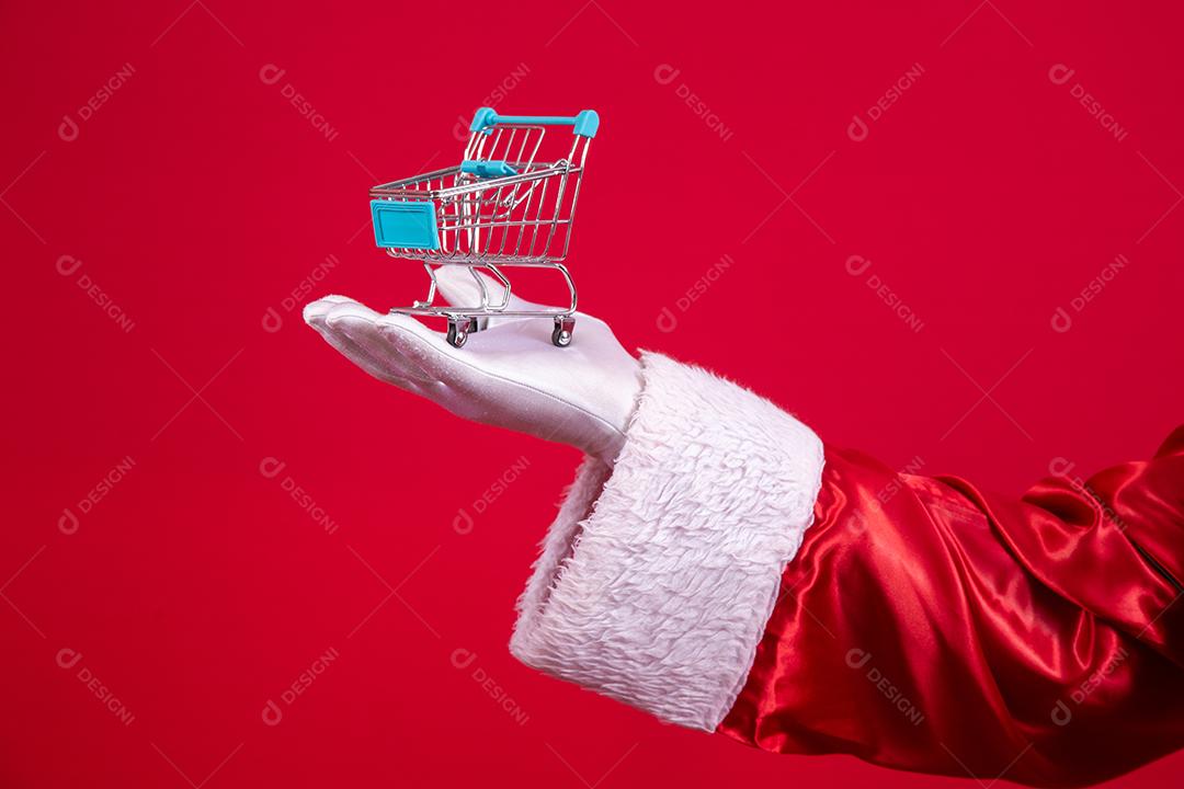 Papai Noel e o supermercado, ele está mostrando um mini carrinho. Natal e conceito de compras.