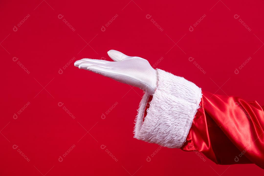Mão enluvada de Papai Noel dando gesticulando sobre fundo vermelho. Tempo festivo para feliz ano novo