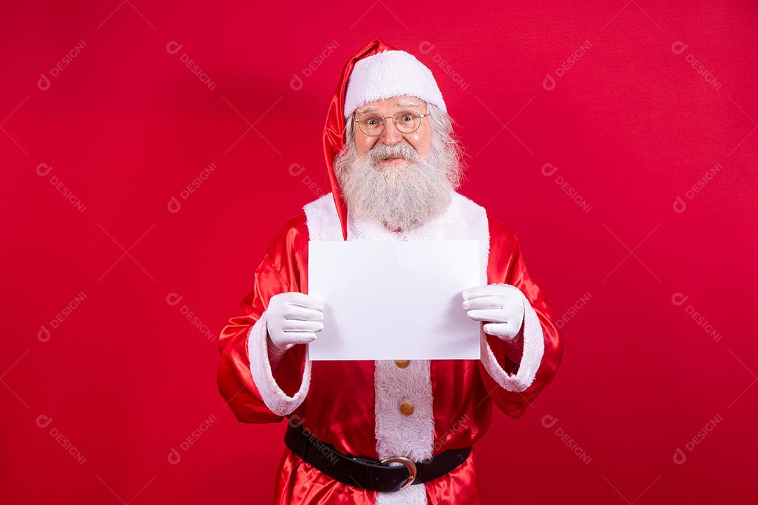 Feliz Papai Noel segurando uma placa em branco isolada em fundo vermelho