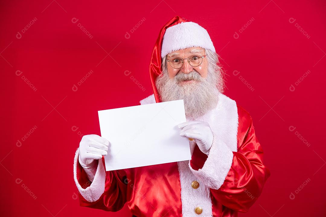 Feliz Papai Noel segurando uma placa em branco isolada em fundo vermelho