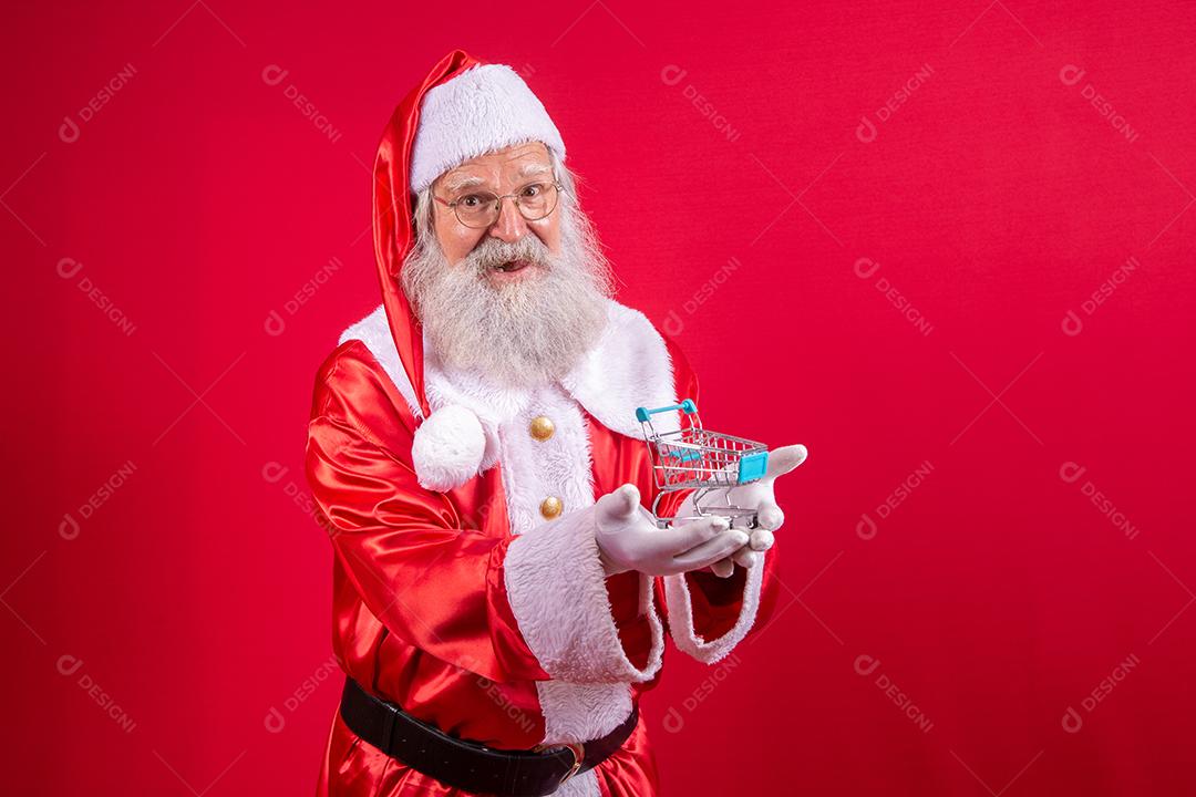 Papai Noel segurando as chaves da nova casa ou apartamento em fundo vermelho.