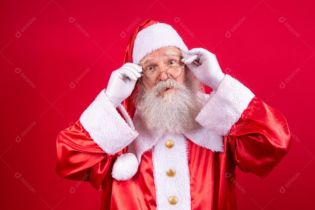 Papai Noel olhando para a câmera. O Natal está chegando. Feliz Natal. Papai Noel está assistindo. Segurando os óculos.