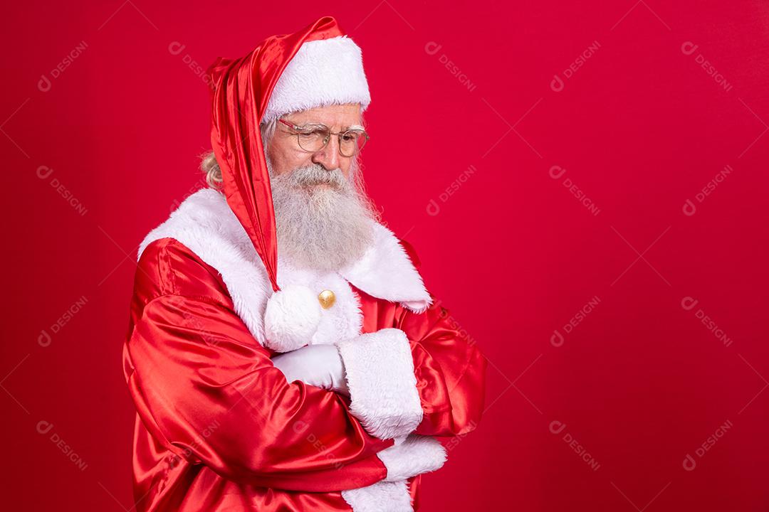 Papai Noel está triste e deprimido sobre fundo vermelho, usando óculos e chapéu.
