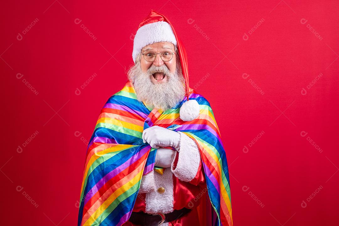 Papai Noel cobrindo com bandeira do orgulho LGBT. Sozinho. Um. Mantendo o punho erguido, cobrindo a bandeira LGBT. Bandeira LGBT + em fundo vermelho. Natal.