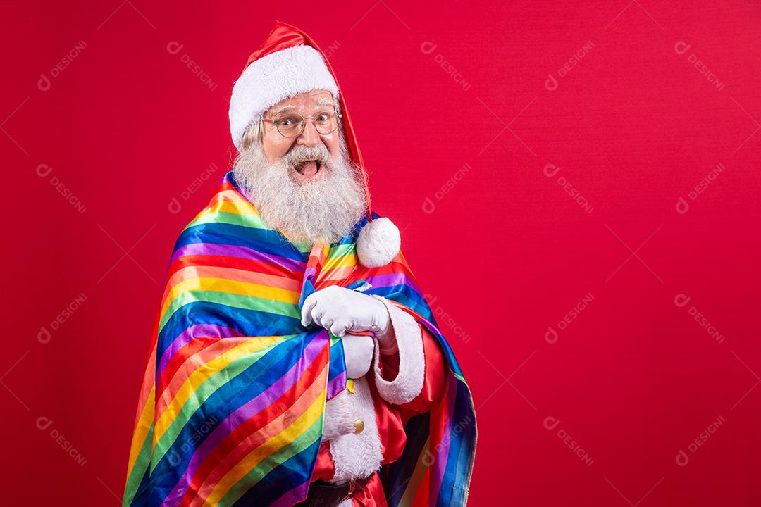 Papai Noel cobrindo com bandeira do orgulho LGBT. Sozinho. Um. Mantendo o punho erguido, cobrindo a bandeira LGBT. Bandeira LGBT + em fundo vermelho. Natal.