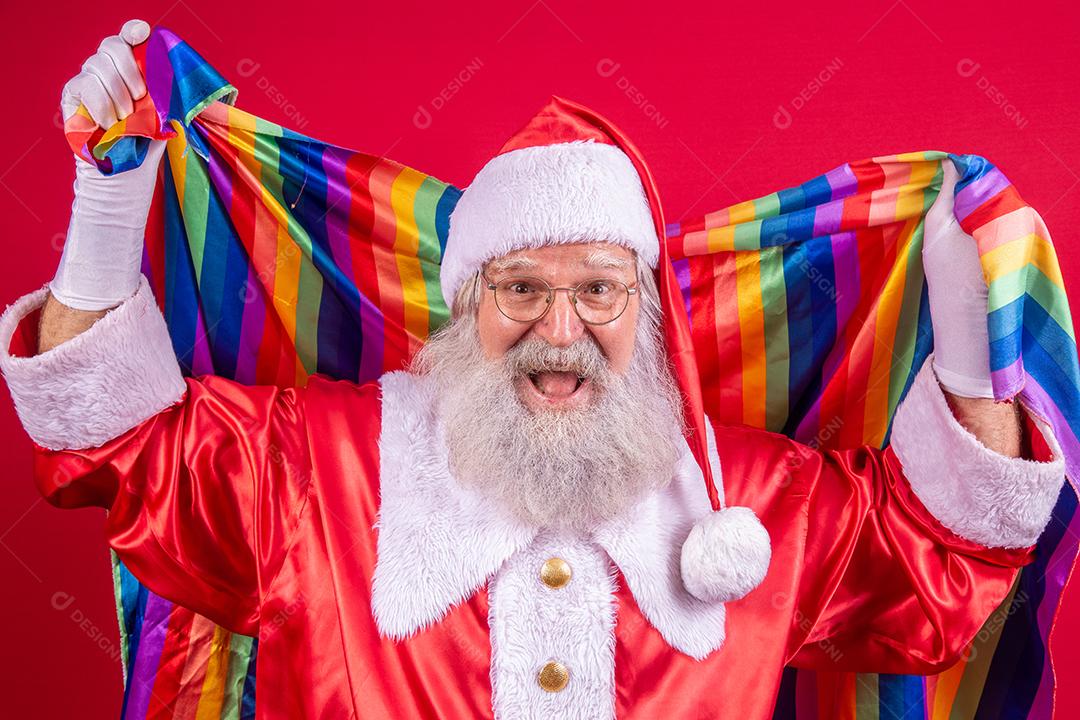 Papai Noel cobrindo com bandeira do orgulho LGBT. Sozinho. Um. Mantendo o punho erguido, cobrindo a bandeira LGBT. Bandeira LGBT + em fundo vermelho. Natal.