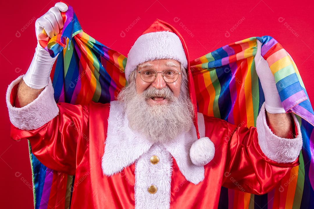 Papai Noel cobrindo com bandeira do orgulho LGBT. Sozinho. Um. Mantendo o punho erguido, cobrindo a bandeira LGBT. Bandeira LGBT + em fundo vermelho. Natal.