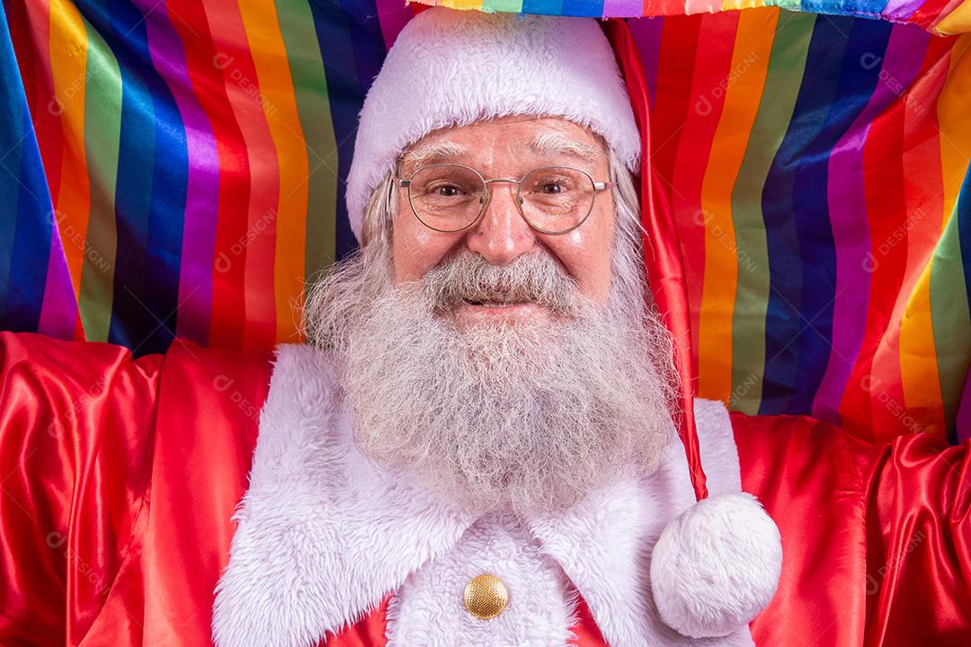 Papai Noel cobrindo com bandeira do orgulho LGBT. Sozinho. Um. Mantendo o punho erguido, cobrindo a bandeira LGBT. Bandeira LGBT + em fundo vermelho. Natal.