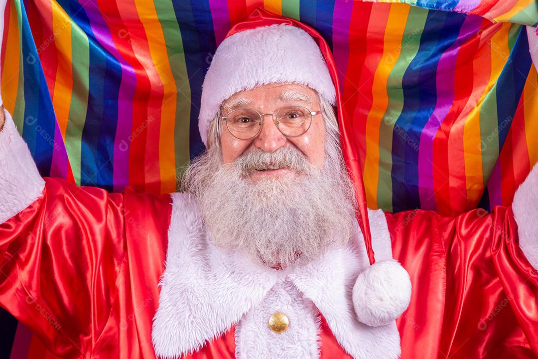 Papai Noel cobrindo com bandeira do orgulho LGBT. Sozinho. Um. Mantendo o punho erguido, cobrindo a bandeira LGBT. Bandeira LGBT + em fundo vermelho. Natal.