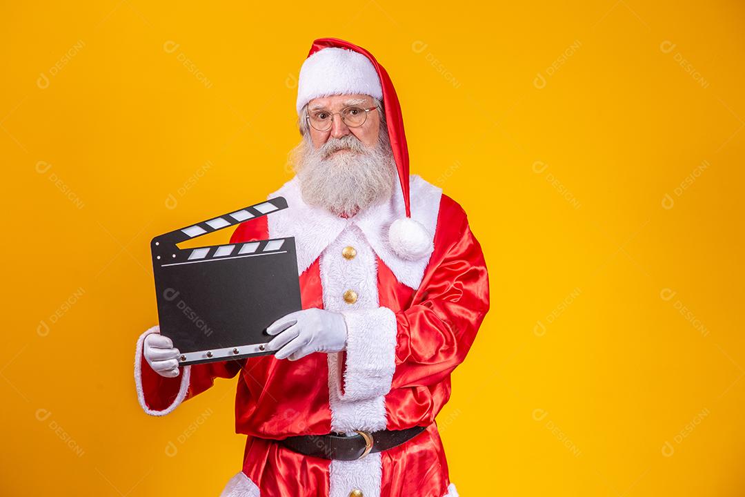 É hora de alguma ação. Alegre idoso Papai Noel posando com uma claquete.