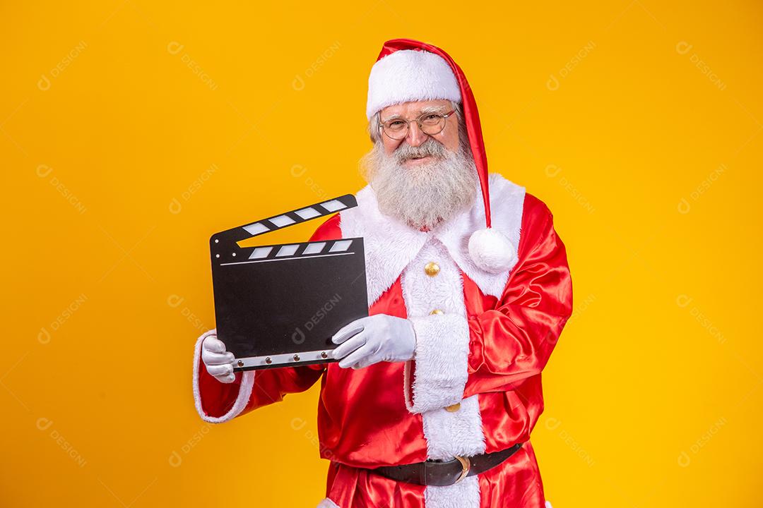 É hora de alguma ação. Alegre idoso Papai Noel posando com uma claquete.