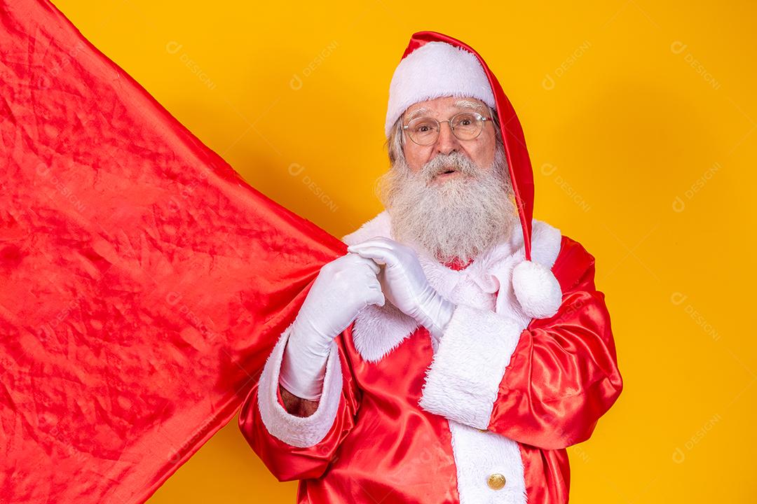 Papai Noel em fundo amarelo, segurando o saco de presente.