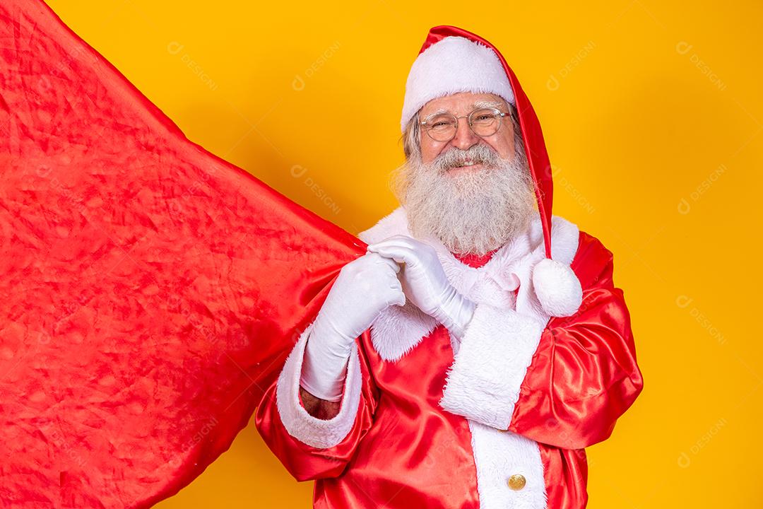 Papai Noel em fundo amarelo, segurando o saco de presente.