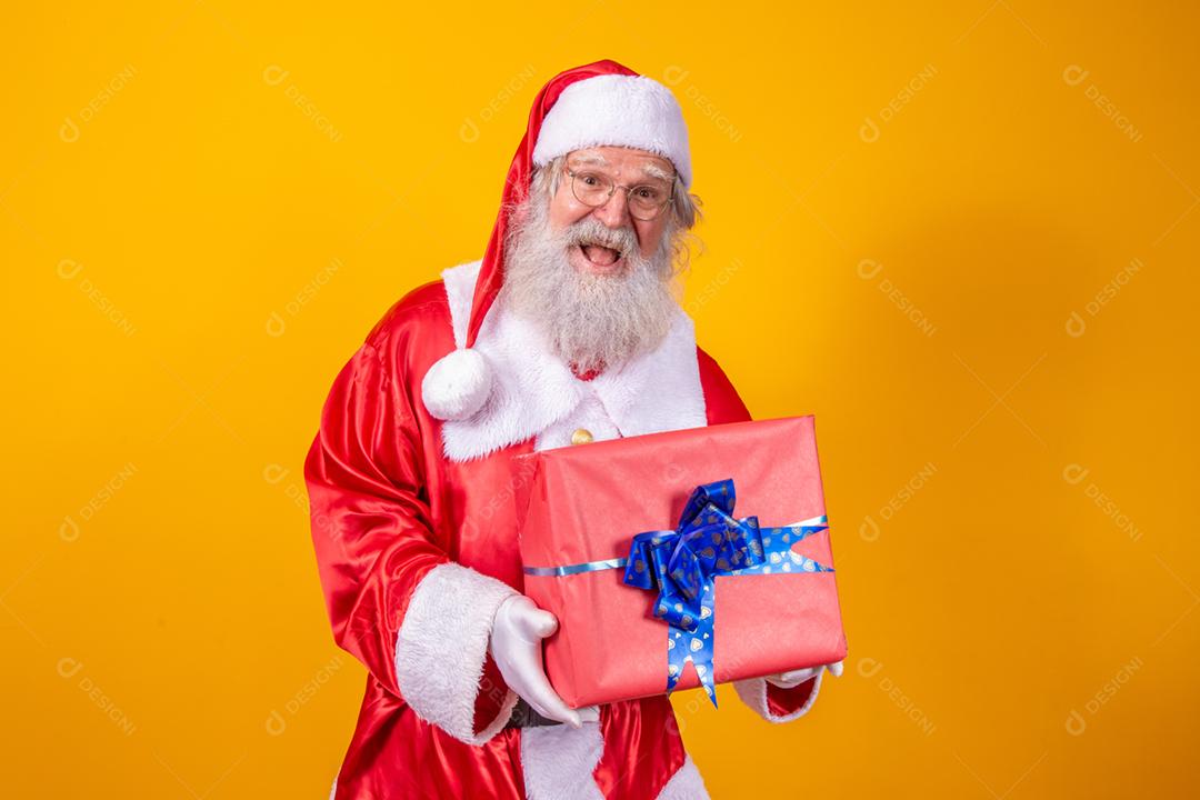 Papai Noel segurando uma caixa de presente em fundo amarelo.