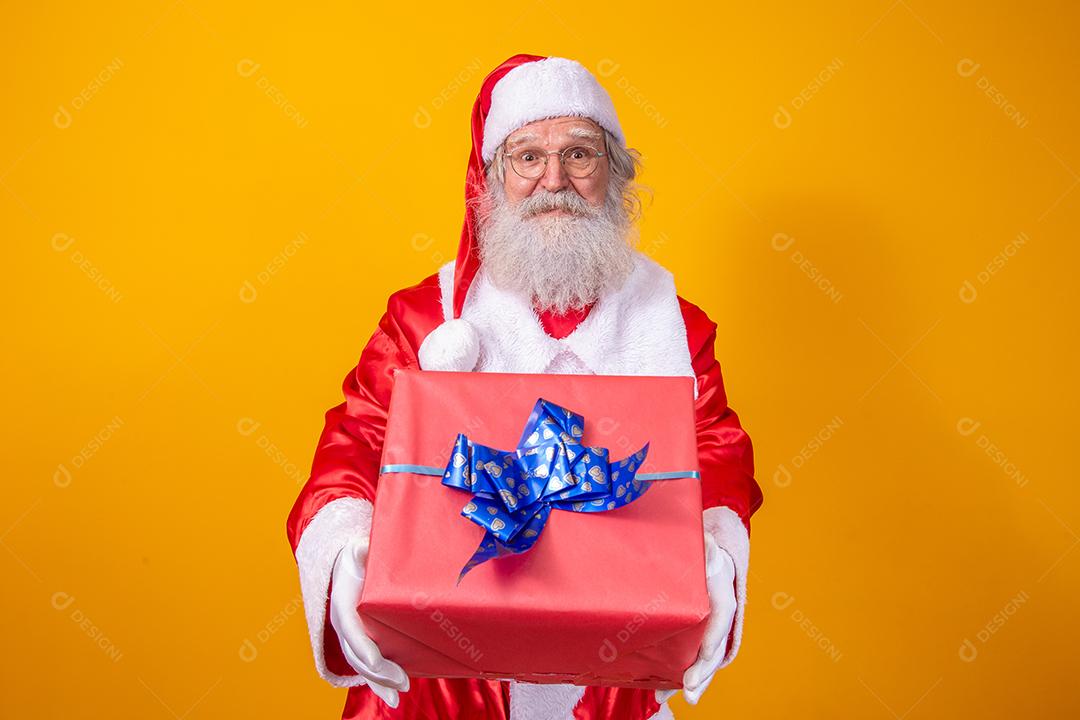 Papai Noel segurando uma caixa de presente em fundo amarelo. Conceito de natal e ano novo