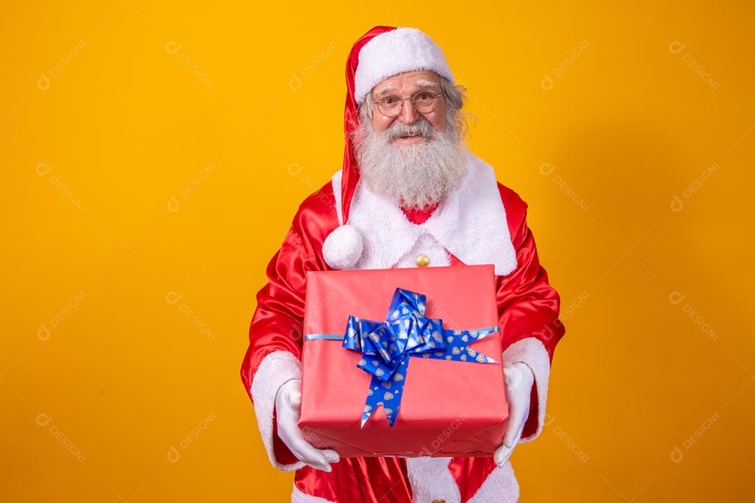 Papai Noel segurando uma caixa de presente em fundo amarelo.