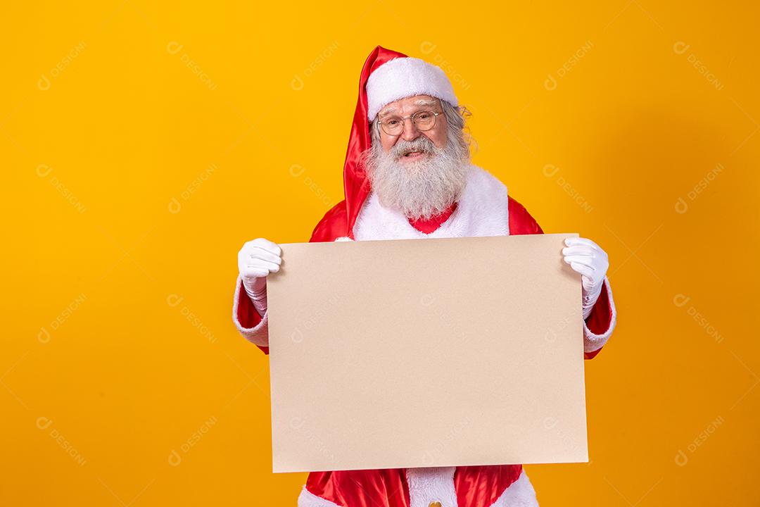 Feliz Papai Noel segurando uma placa em branco isolada em fundo amarelo