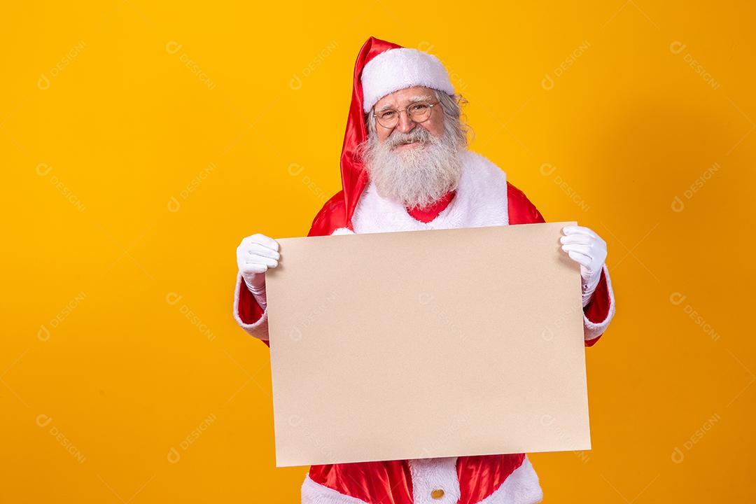 Feliz Papai Noel segurando uma placa em branco isolada em fundo amarelo