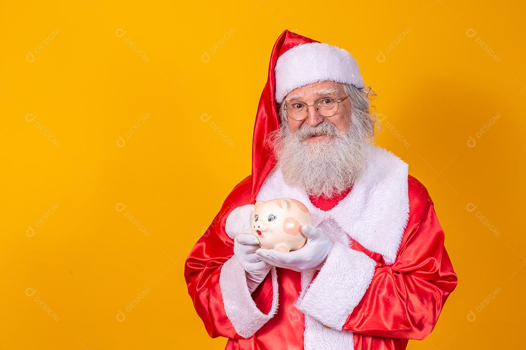 Papai Noel colocando moedas em um cofrinho de cerâmica. Conceito de poupança para o final do ano. Gastando no Natal. Gasto em presentes de Natal.