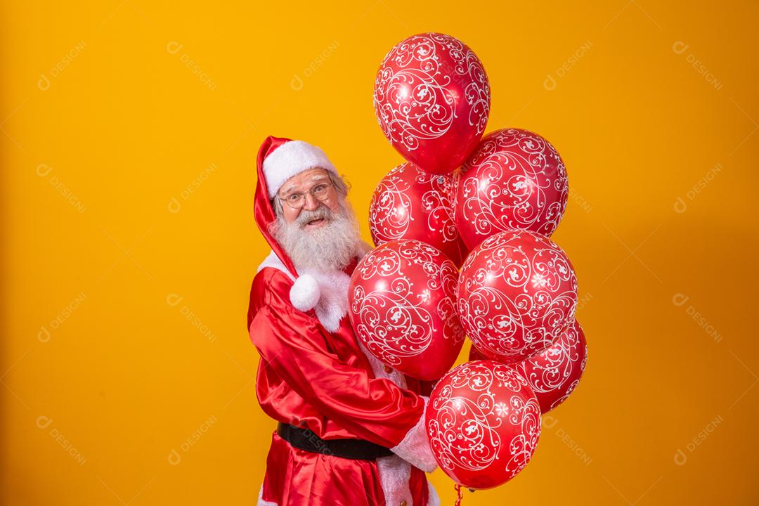 Santa Claus on yellow background holding red balloons.