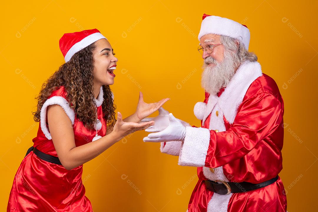 Feliz Natal. Jovem noelete e verdadeiro Papai Noel interagindo jogando em fundo amarelo