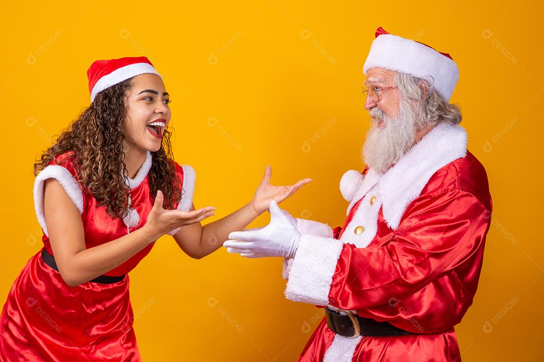 Feliz Natal. Jovem noelete e verdadeiro Papai Noel interagindo jogando em fundo amarelo