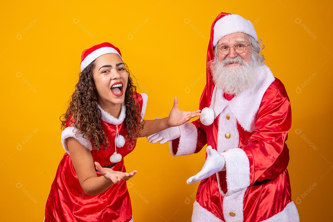 Feliz Natal. Jovem noelete e verdadeiro Papai Noel interagindo jogando em fundo amarelo