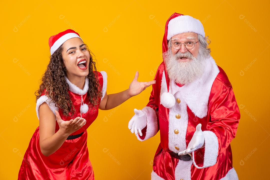 Feliz Natal. Jovem noelete e verdadeiro Papai Noel interagindo jogando em fundo amarelo