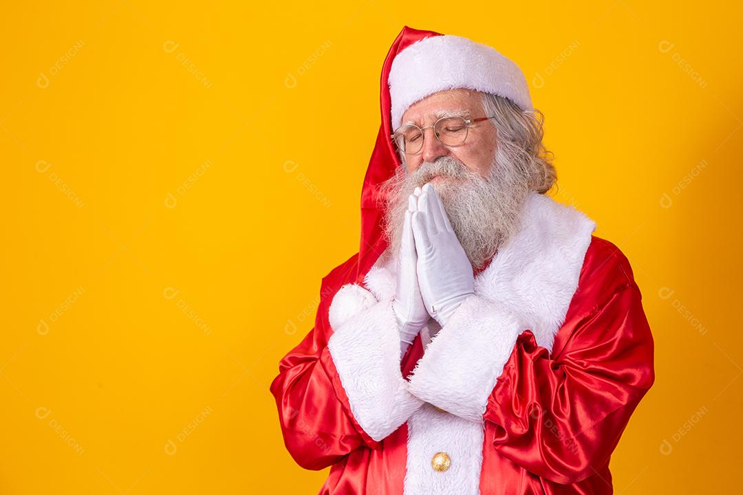 Papai Noel rezando em fundo amarelo. Fé