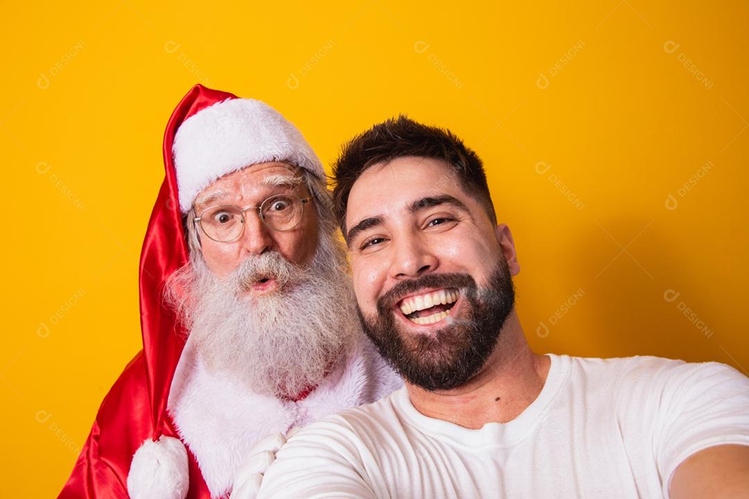 Garoto fazendo uma selfie com o verdadeiro Papai Noel em fundo amarelo