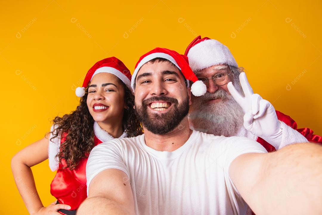 casal de namorados fazendo uma selfie com o Papai Noel.
