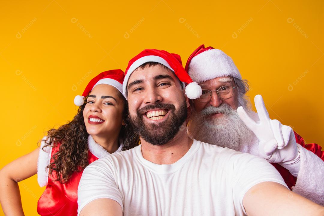 casal de namorados fazendo uma selfie com o Papai Noel.