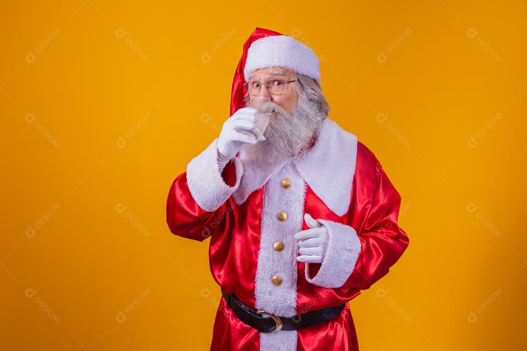 Papai Noel bebendo um copo de água no fundo amarelo