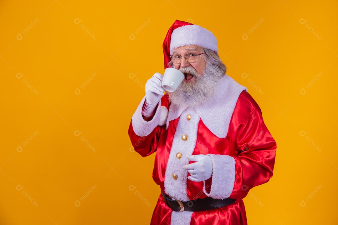 Papai Noel tomando um café em fundo amarelo com espaço livre