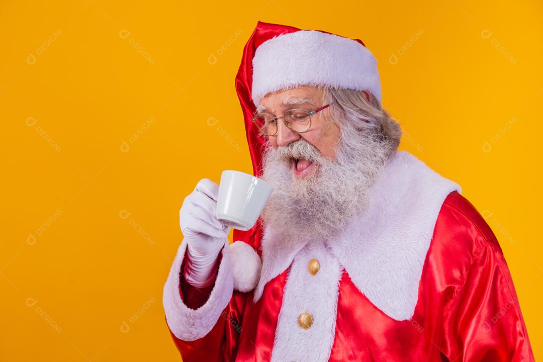 Papai Noel tomando um café em fundo amarelo com espaço livre