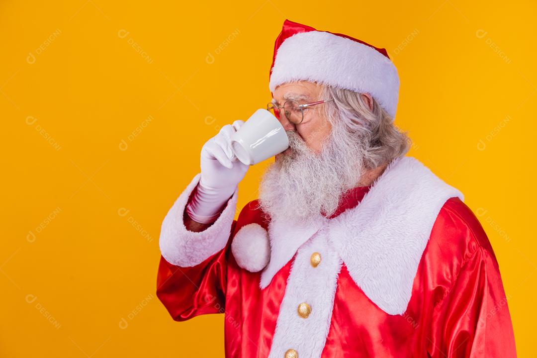 Papai Noel tomando um café em fundo amarelo com espaço livre