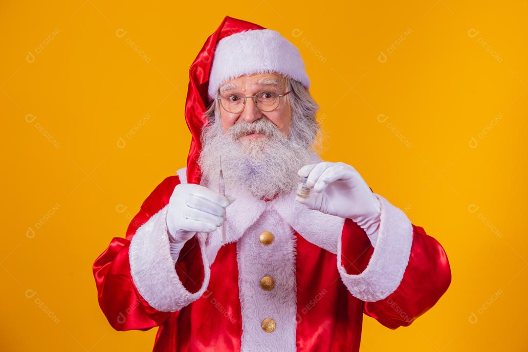 Papai Noel com seringa e vacina na mão. Papai Noel segurando