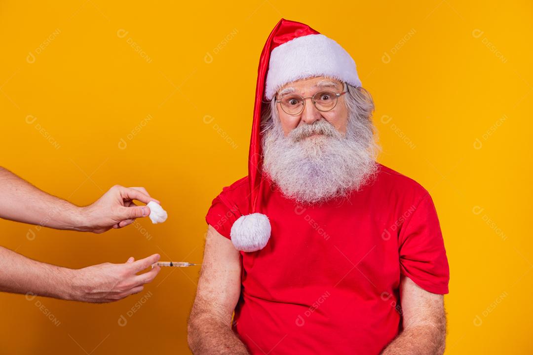 Papai Noel sendo vacinado com injeção.